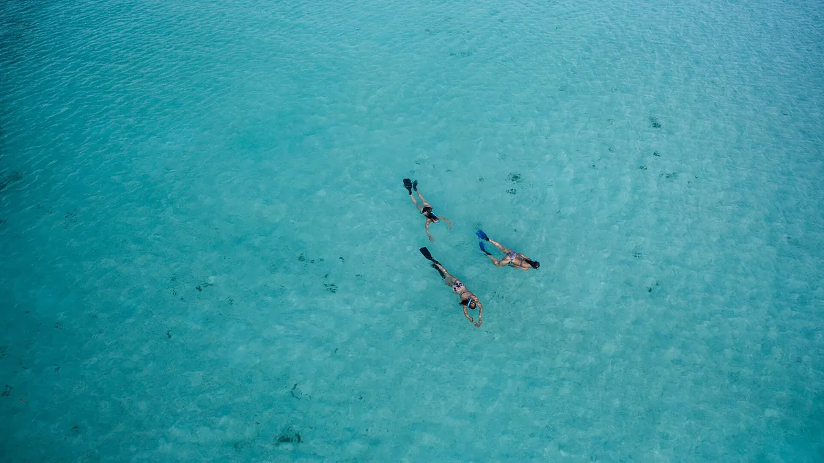 Snorkellers in a turquoise lagoon in the Maldives